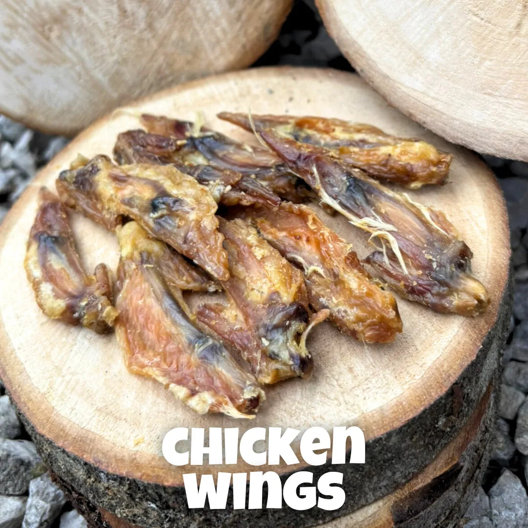 Natural dog treats – premium 100% chicken wings, air-dried and displayed on rustic wooden logs, perfect for chewing enrichment and dental health.