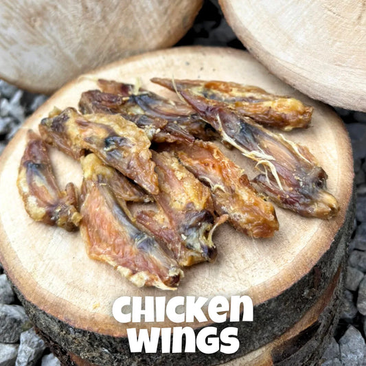 Natural dog treats – premium 100% chicken wings, air-dried and displayed on rustic wooden logs, perfect for chewing enrichment and dental health.